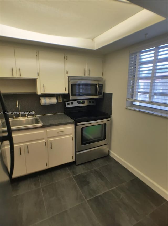 1821 Jefferson Ave Unit 205, Miami Beach, FL 33139 - kitchen featuring stainless steel appliances, dark tile patterned flooring, dark countertops, and white cabinetry