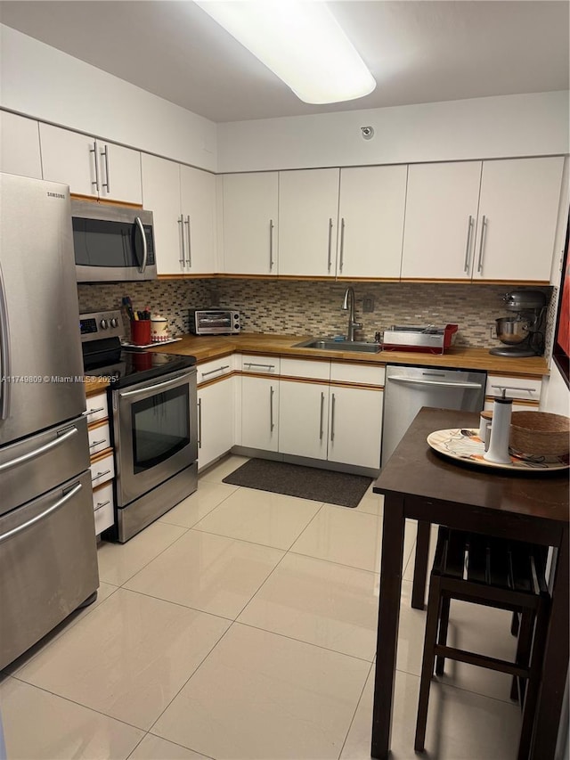 3530 Mystic Pointe Dr Unit 2303, Aventura, FL 33180 - kitchen featuring stainless steel appliances, a sink, butcher block counters, and decorative backsplash