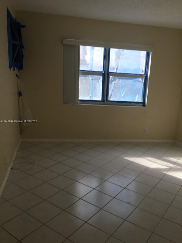 empty room featuring tile patterned flooring and baseboards