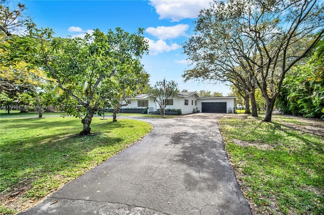 view of front of property featuring aphalt driveway, an attached garage, and a front yard