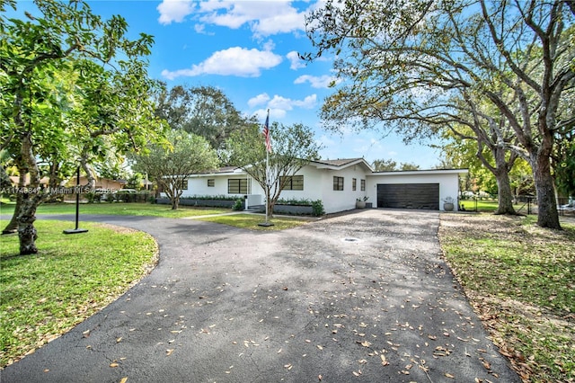 single story home featuring aphalt driveway, a garage, a front yard, and stucco siding