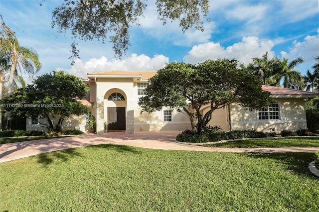 view of front of property featuring decorative driveway, a front yard, and stucco siding