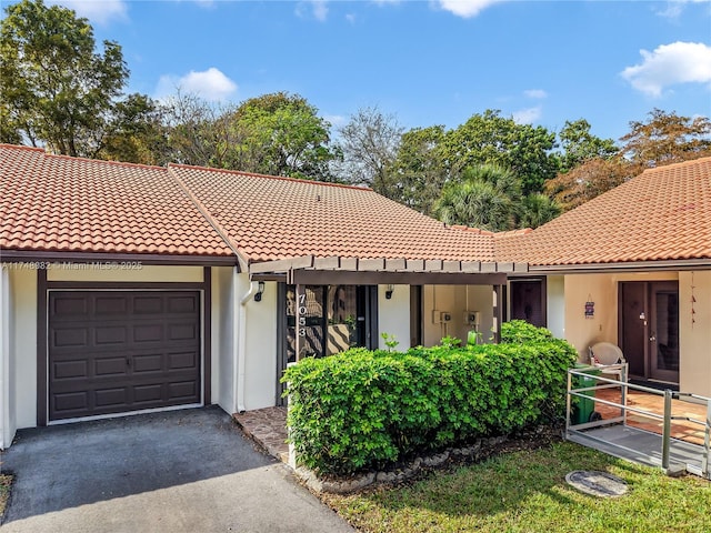 view of front of home with aphalt driveway, an attached garage, and a tile roof