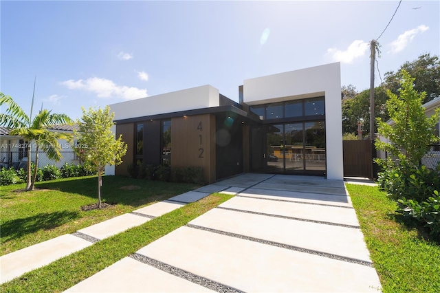 view of front of home with a front yard, fence, and stucco siding