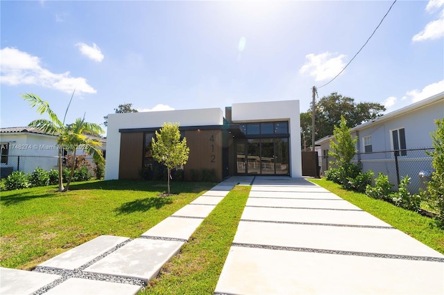 modern home with fence, a front lawn, and stucco siding