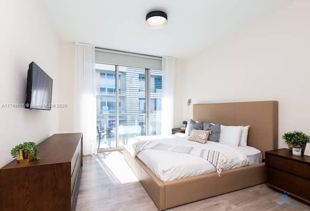 bedroom with access to outside, a wall of windows, and light wood-type flooring