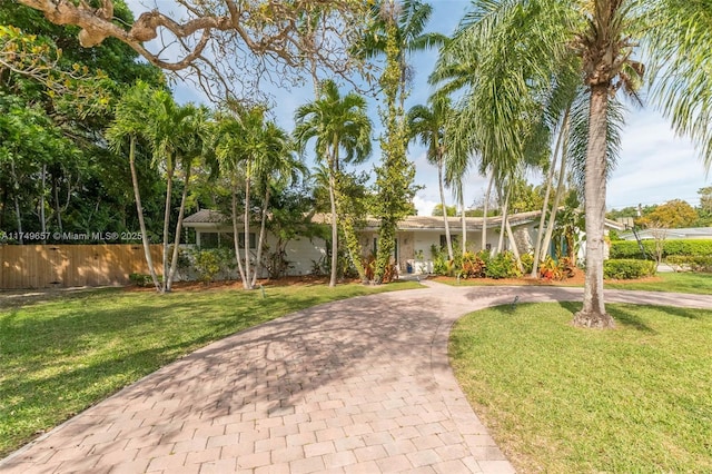 view of front of house featuring fence, decorative driveway, and a front yard