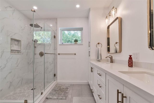 bathroom with recessed lighting, baseboards, a marble finish shower, and double vanity