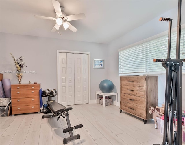 exercise area with light wood finished floors and ceiling fan