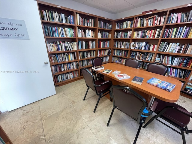 home office with a paneled ceiling and wall of books