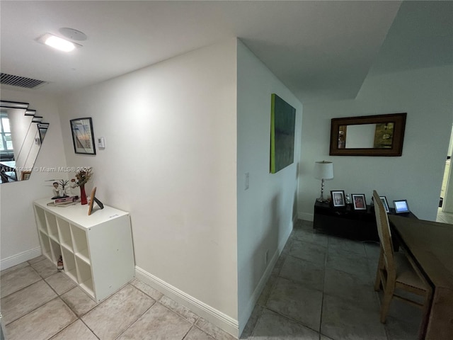 hallway with light tile patterned flooring, baseboards, and visible vents