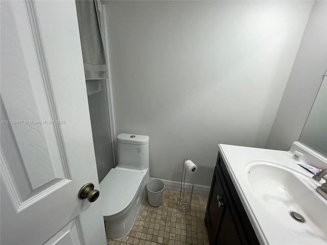 half bath with toilet, vanity, and baseboards