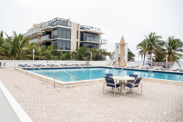 community pool with a patio and fence