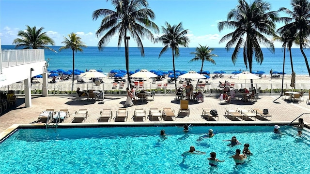 community pool with a water view and fence