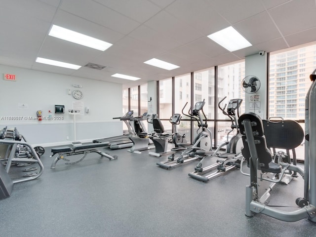exercise room featuring visible vents, a drop ceiling, and expansive windows