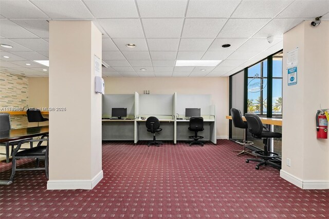 carpeted home office featuring baseboards and a drop ceiling
