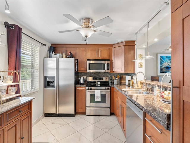 kitchen featuring dark stone counters, stainless steel appliances, brown cabinetry, and a sink