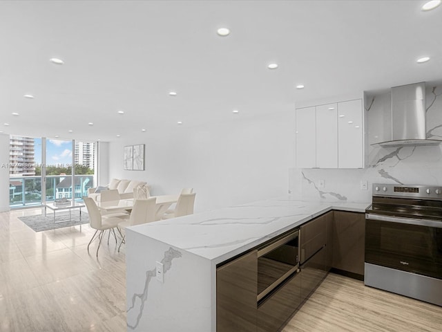 kitchen featuring white cabinets, decorative backsplash, stainless steel electric range oven, modern cabinets, and wall chimney range hood