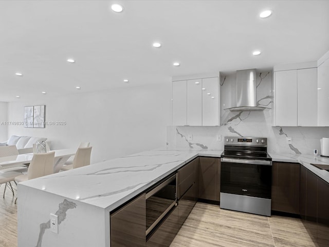 kitchen with white cabinets, wall chimney exhaust hood, modern cabinets, light stone counters, and stainless steel electric range