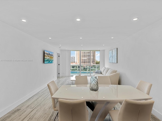 dining space with light wood finished floors, baseboards, floor to ceiling windows, and recessed lighting