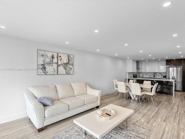 living room with recessed lighting, light wood finished floors, and baseboards