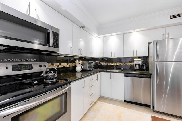 kitchen featuring a sink, white cabinetry, appliances with stainless steel finishes, tasteful backsplash, and crown molding