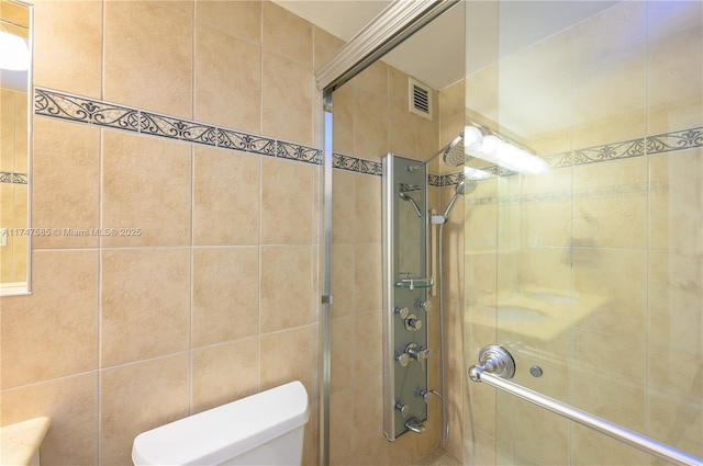 full bath with visible vents, a tile shower, and toilet