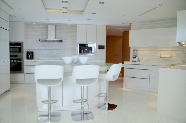 kitchen featuring light tile patterned floors, wall chimney exhaust hood, a breakfast bar area, and modern cabinets