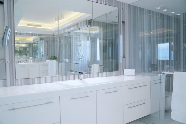 full bath featuring a shower, a raised ceiling, and vanity