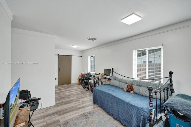bedroom featuring visible vents, a barn door, and wood finished floors