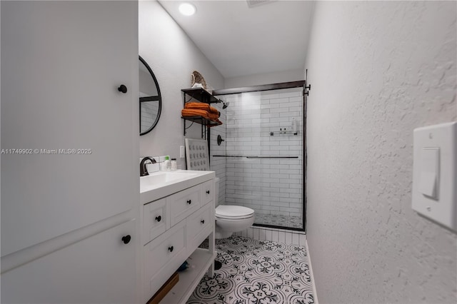 full bathroom featuring a textured wall, toilet, tile patterned floors, vanity, and a shower stall