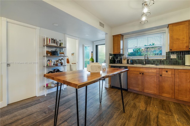 kitchen with tasteful backsplash, visible vents, brown cabinetry, and stainless steel dishwasher