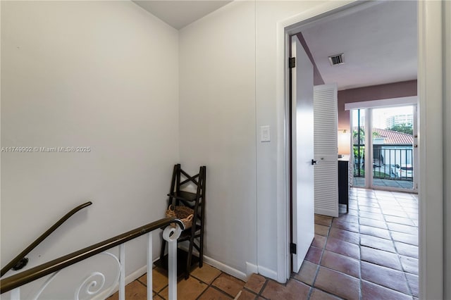 hall featuring an upstairs landing, visible vents, and baseboards