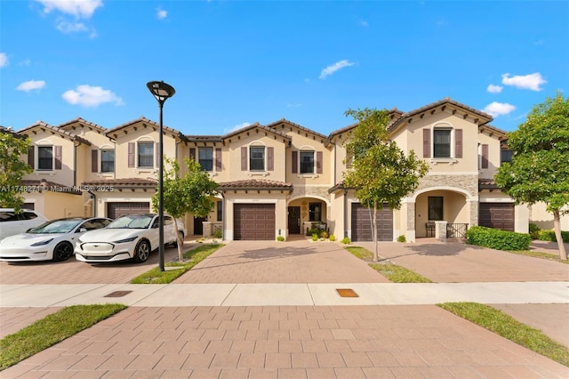 mediterranean / spanish-style house featuring a garage, a tile roof, driveway, and stucco siding