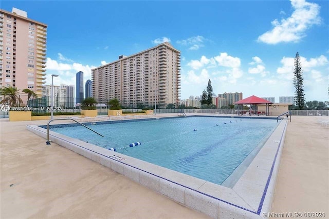 pool featuring a gazebo, fence, and a city view