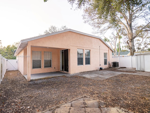 back of house with cooling unit, a fenced backyard, a gate, stucco siding, and a patio area