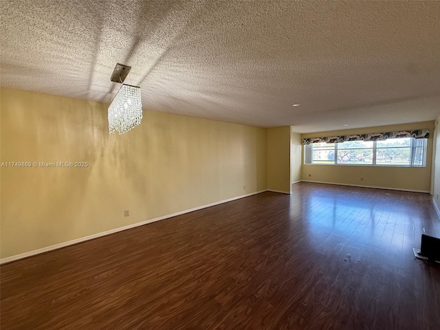 unfurnished room with dark wood finished floors, a textured ceiling, and baseboards