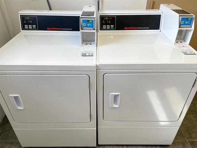 community laundry room featuring washer and dryer and dark tile patterned flooring