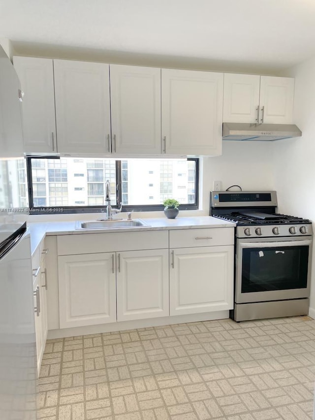 kitchen featuring light countertops, white cabinetry, a sink, gas range, and under cabinet range hood