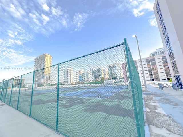 view of sport court featuring a city view and fence