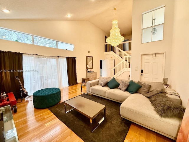 living area with a chandelier, wood finished floors, stairs, high vaulted ceiling, and recessed lighting