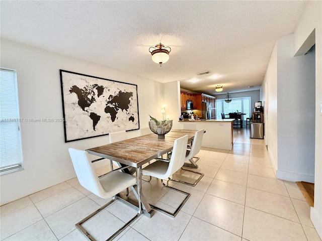 dining space featuring a textured ceiling, visible vents, and light tile patterned floors