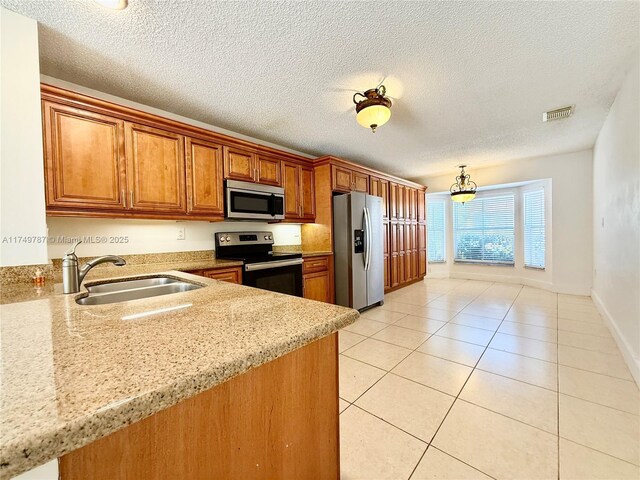 kitchen with brown cabinets, stainless steel appliances, visible vents, a sink, and light tile patterned flooring