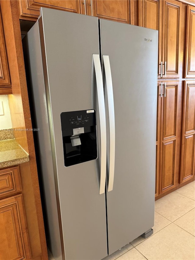 interior details with brown cabinets, light stone counters, and stainless steel fridge
