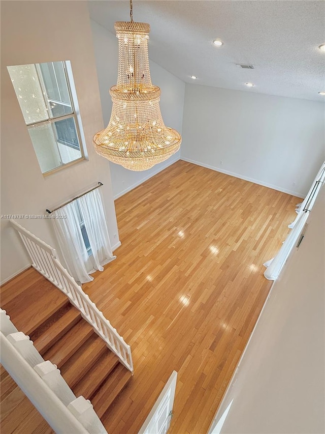 interior space with baseboards, visible vents, an inviting chandelier, light wood-style floors, and stairs
