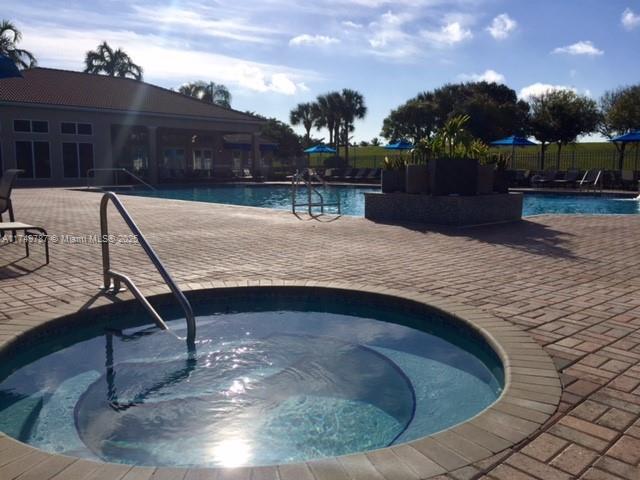 pool featuring fence, a hot tub, and a patio area