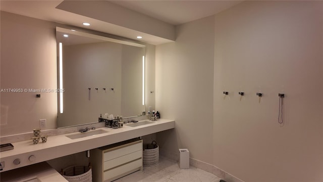 bathroom with baseboards, double vanity, a sink, and recessed lighting