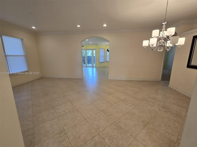 spare room with arched walkways, crown molding, and baseboards