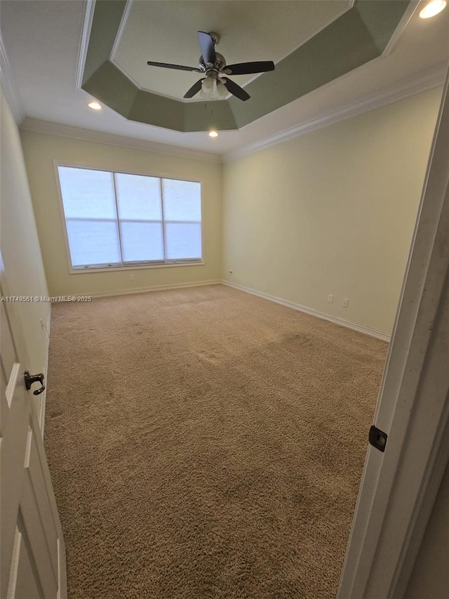 carpeted empty room featuring recessed lighting, a ceiling fan, baseboards, ornamental molding, and a raised ceiling