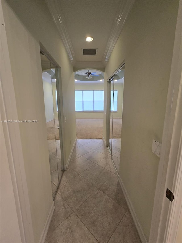 corridor featuring visible vents, crown molding, baseboards, and light tile patterned floors